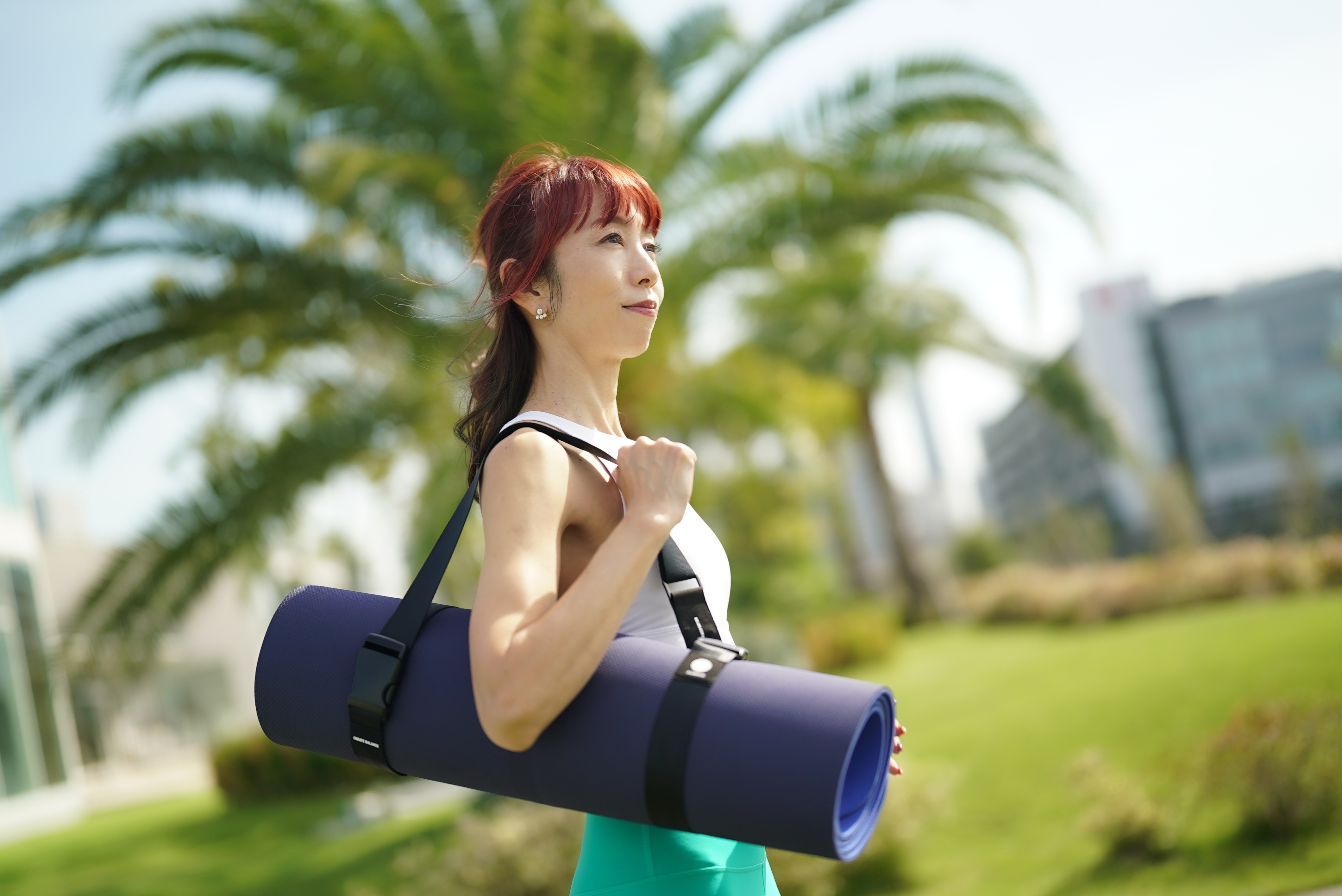 青空の下でヨガマットを持つ様子